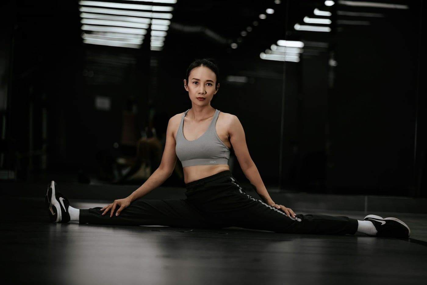 Woman holding a floor split stretch in a dimly lit gym